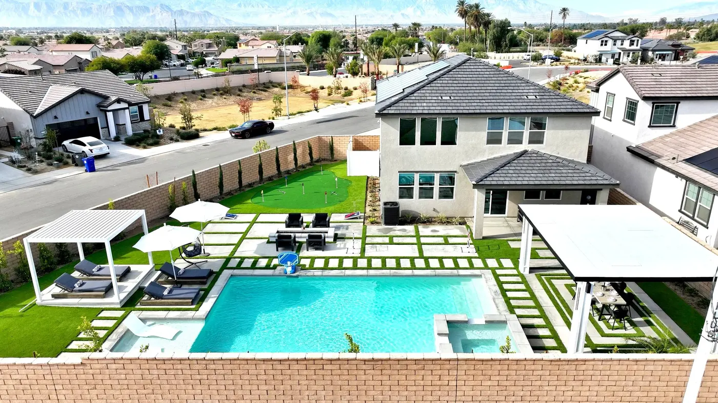 Pool, turf and shade sails in a spacious backyard