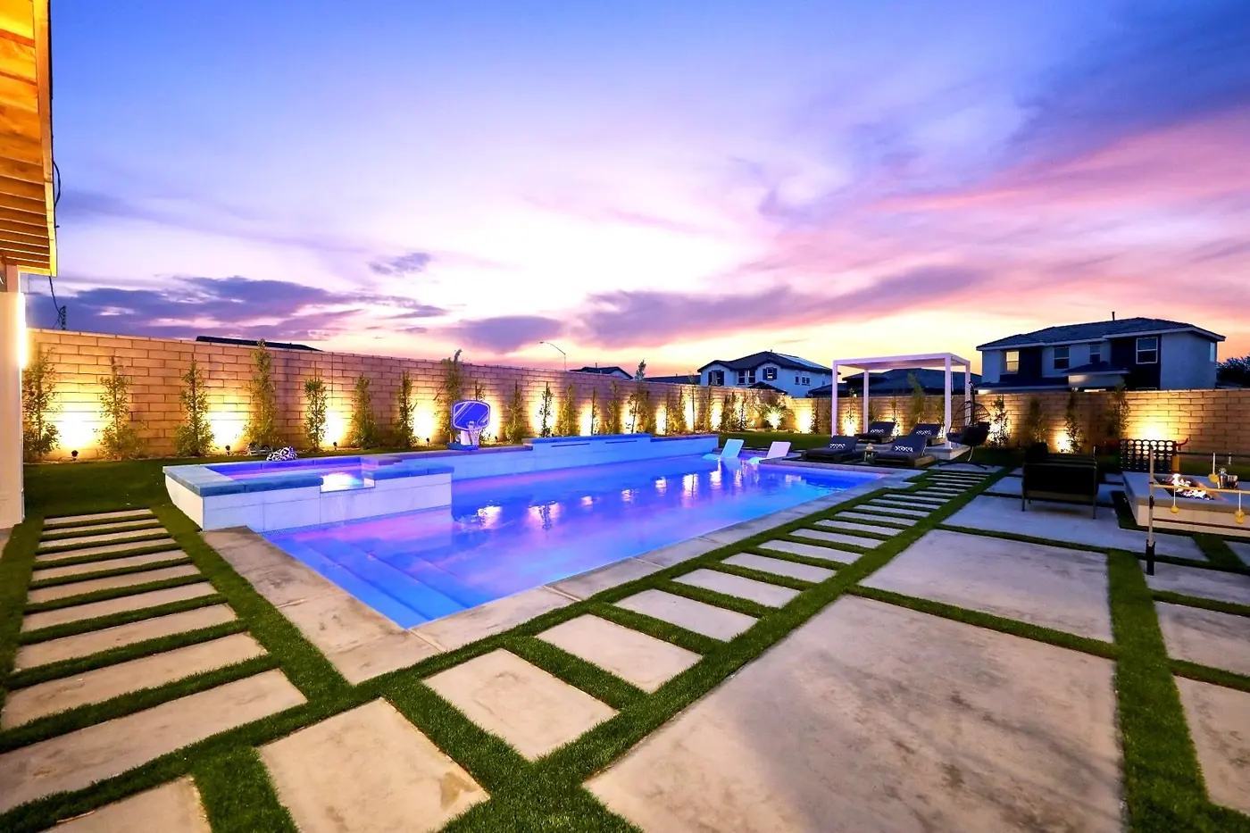 Pool and paver terrace under a pink and violet sky