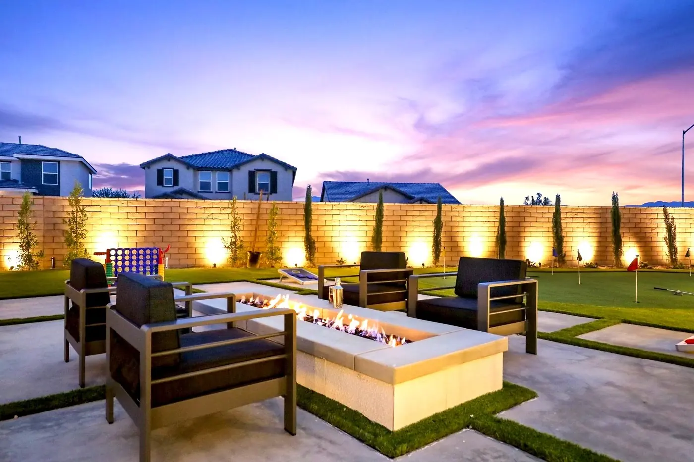 Fire pit lounge with glowing wall lighting at dusk