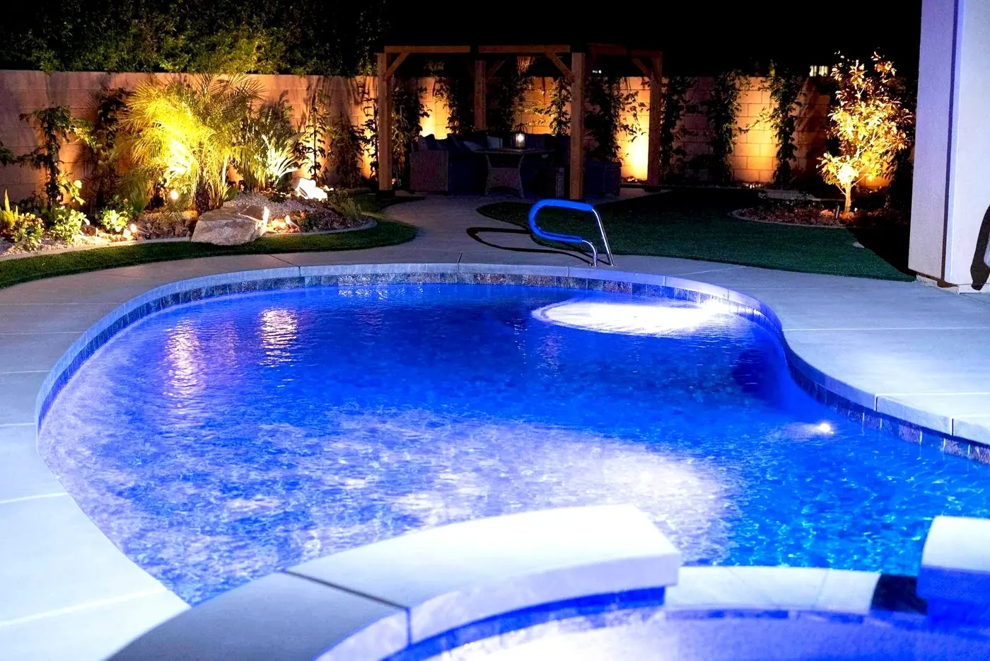 Piscina de forma libre con iluminación LED azul y paisaje iluminado