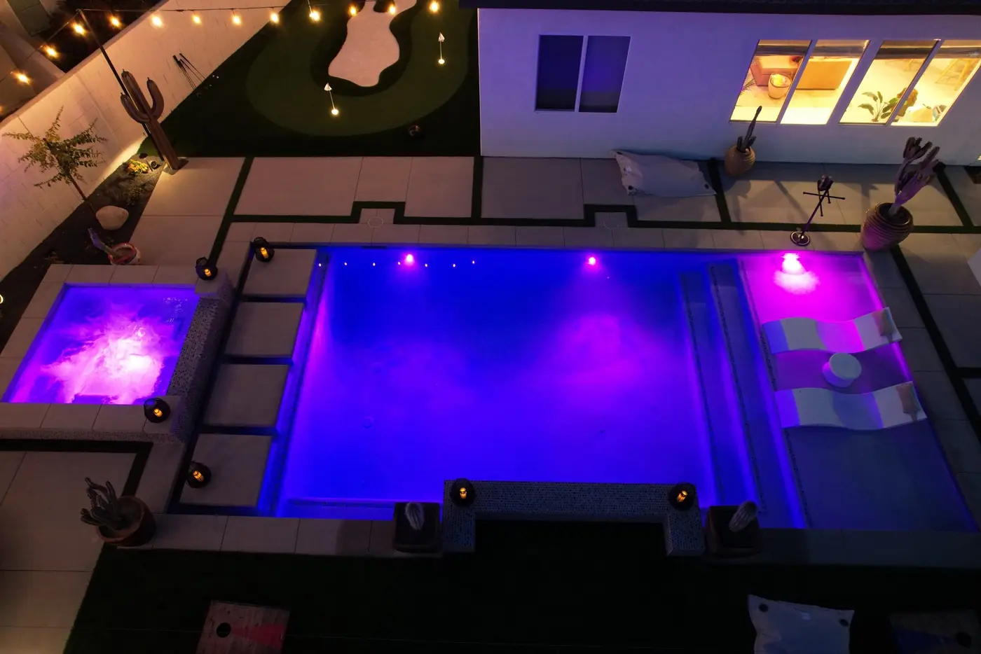 Aerial of a purple-lit pool and spa at night