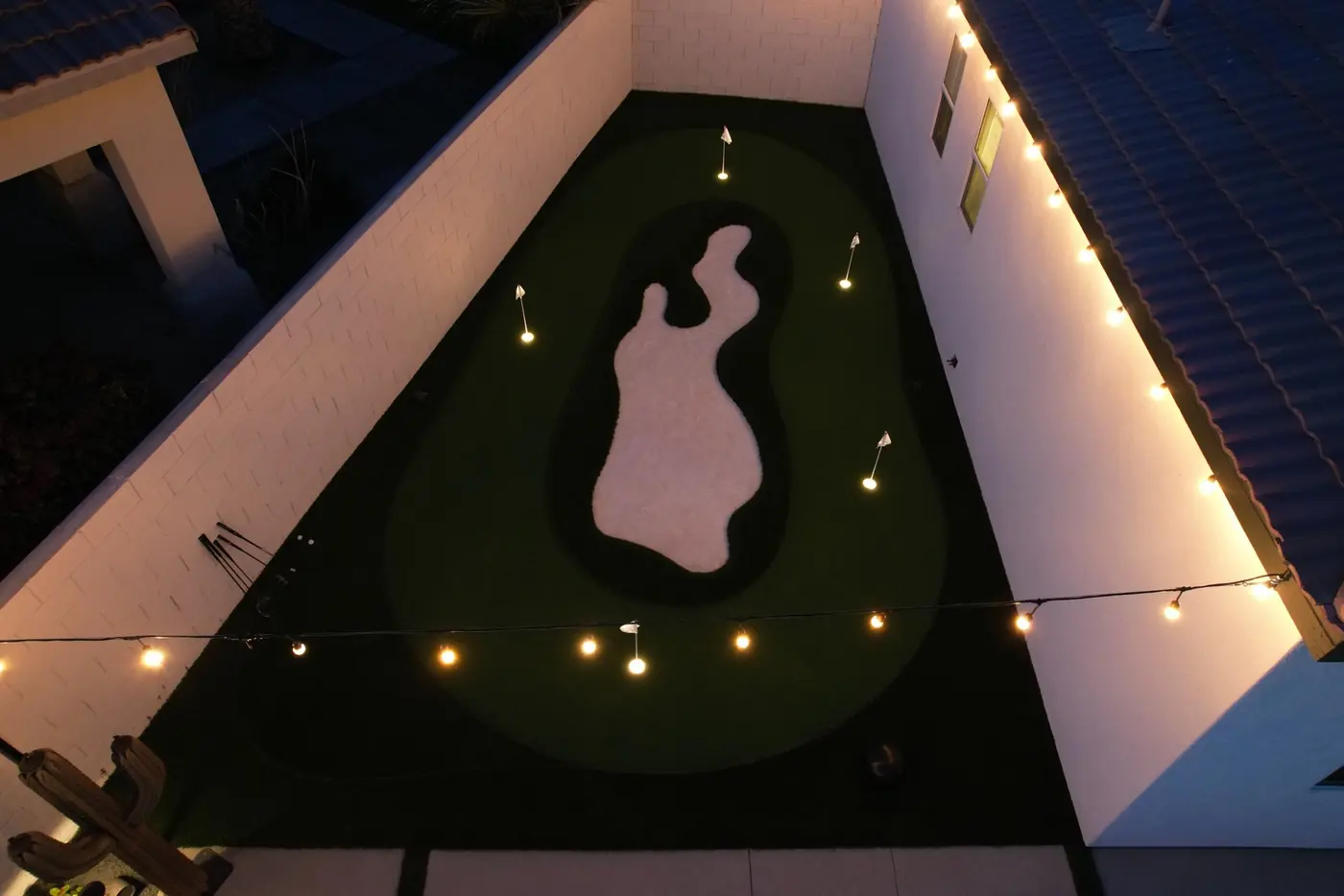 Putting green lit by string lights at night