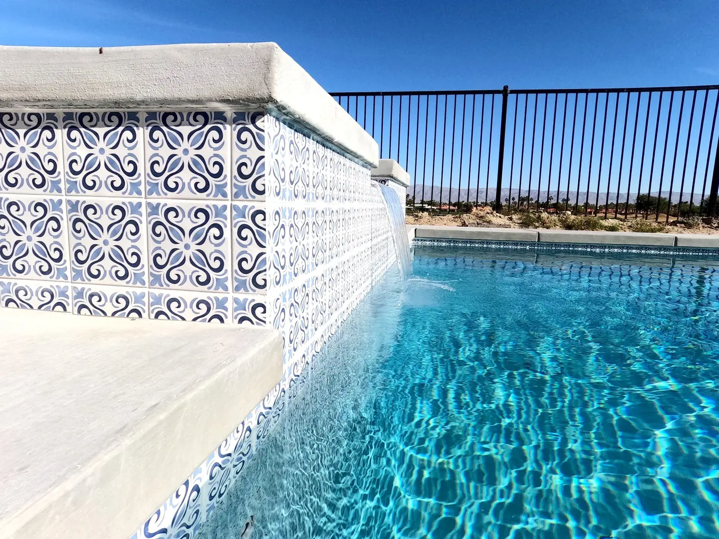 Pool with a blue patterned tile wall and sheer waterfall
